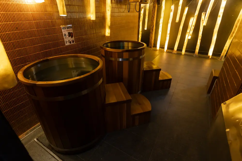 Wooden ice bath tubs beneath glowing amber columns at Wellmax, Bangkok